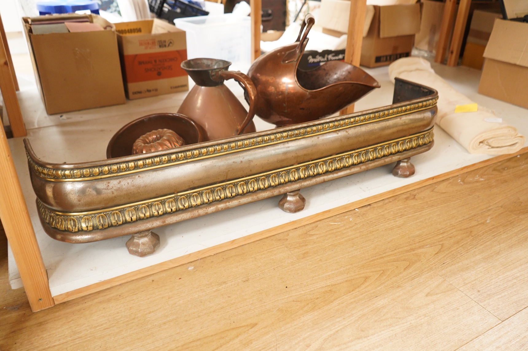 A collection of metalware to include a steel and brass fender, a helmet scuttle, 19th century jelly mould and a harvest jug
